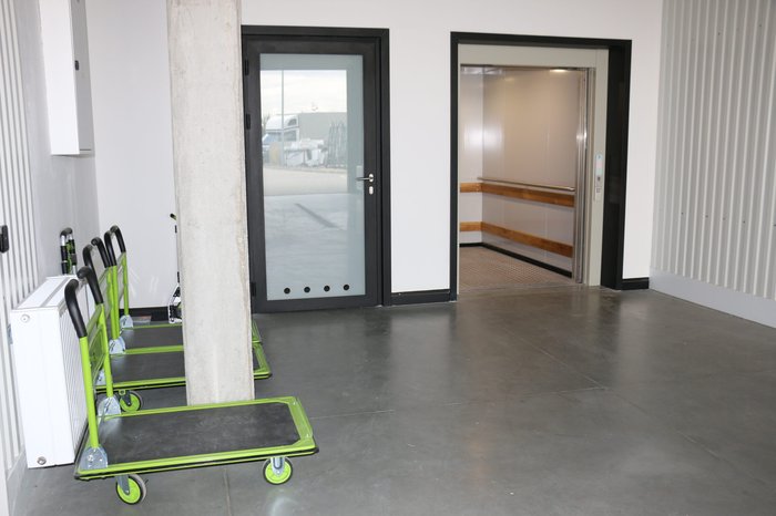 Wejście do hali magazynowej z wózkami transportowymi